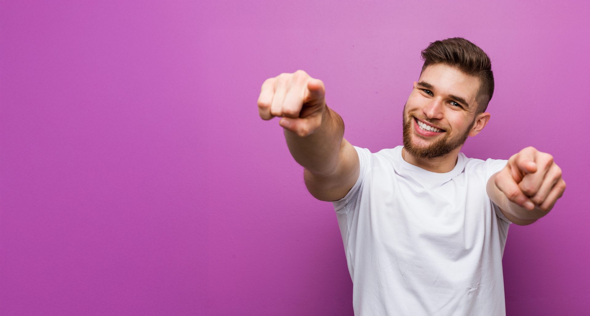 Young handsome caucasian man cheerful smiles pointing to front.